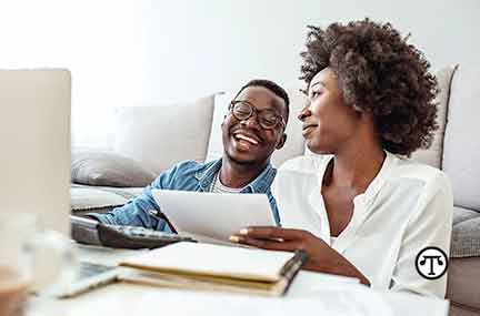 man and woman laughing at their finances on the computer
